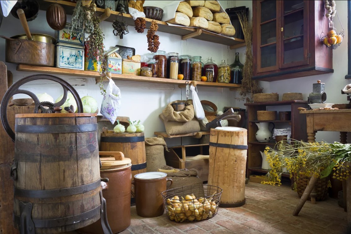Traditional root cellar with wooden barrels, ceramic crocks, dried herbs and stored onions