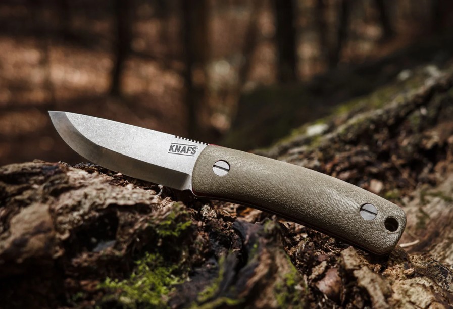 Fixed blade bushcraft knife resting on a moss covered log after a day of work