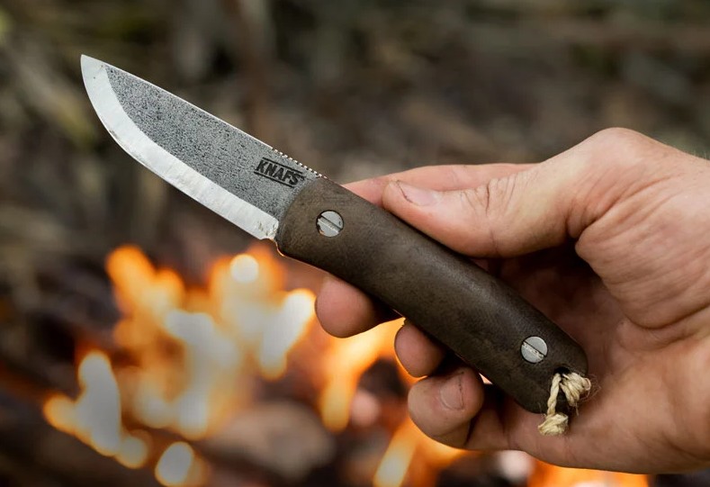 Fixed blade knife held beside a fire during field edge maintenance