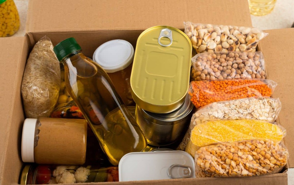 Cardboard emergency food box packed with canned goods, cooking oil, grains and dried legumes