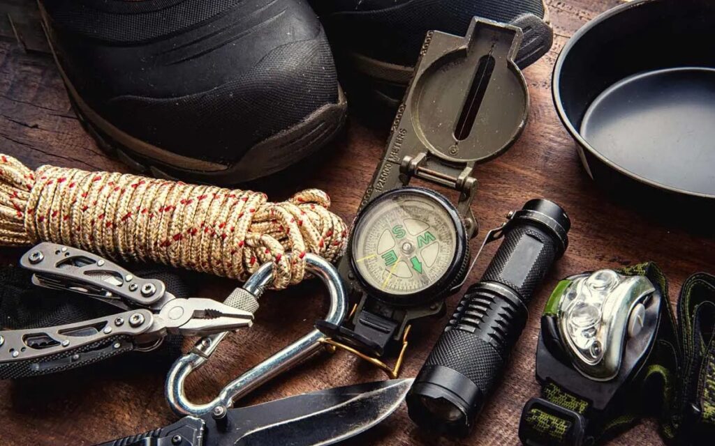 A household emergency kit emptied out and counted: boots, compass, paracord, flashlight, headlamp and a multitool